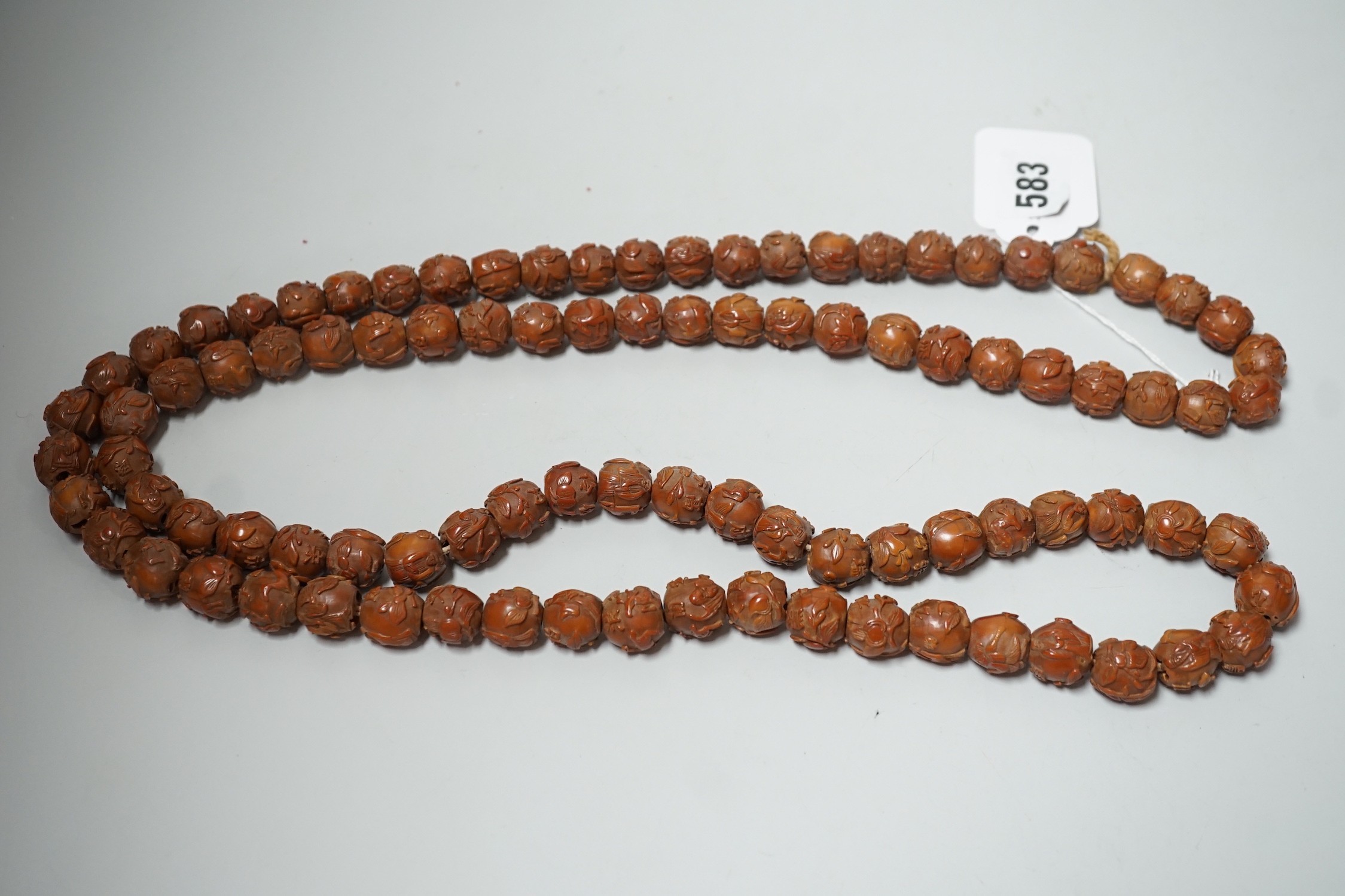 A Chinese necklace of 94 carved coquilla nuts/peach stones